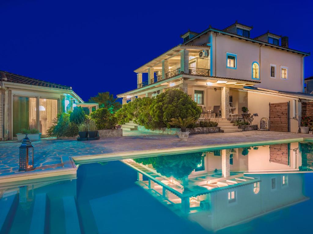 a house with a swimming pool at night at Eleni's Family Villa in Laganas