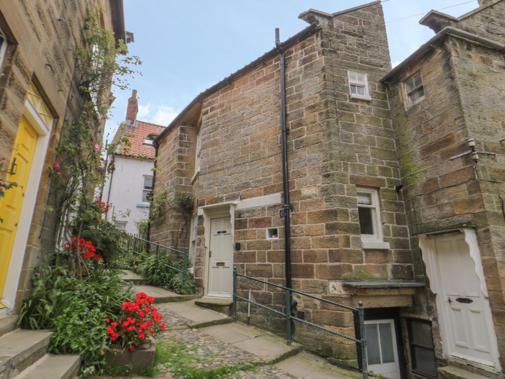 an old brick building with red flowers in front of it at Oakridge Cottage in Whitby