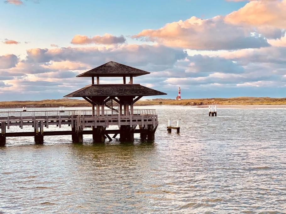 a pier in the water with a lighthouse in the background at Ysermonde Fisherman's Cottage in Nieuwpoort