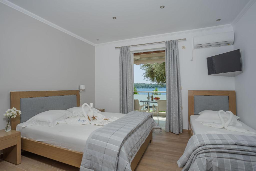 two beds in a bedroom with a view of the ocean at Mare Vita Apartments in Nydri