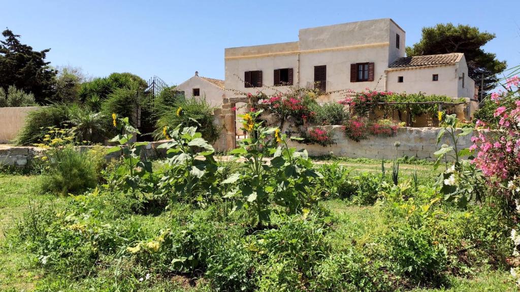 an old house with flowers in front of a yard at Villa Salinara in Marsala