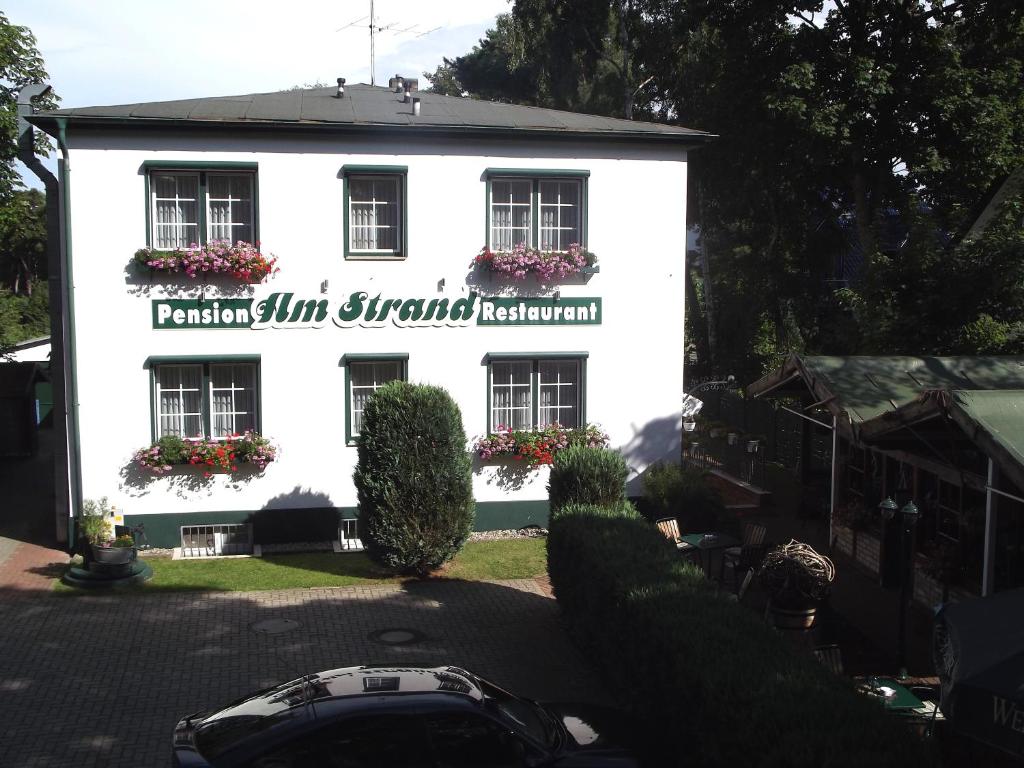 un edificio blanco con un cartel en el costado en Pension Am Strand, en Juliusruh