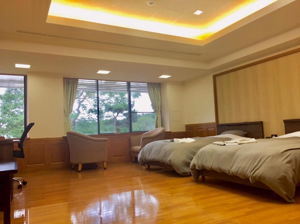 函南町にあるファスティングホテル海の杜のベッド2台と大きな窓が備わるホテルルームです。
