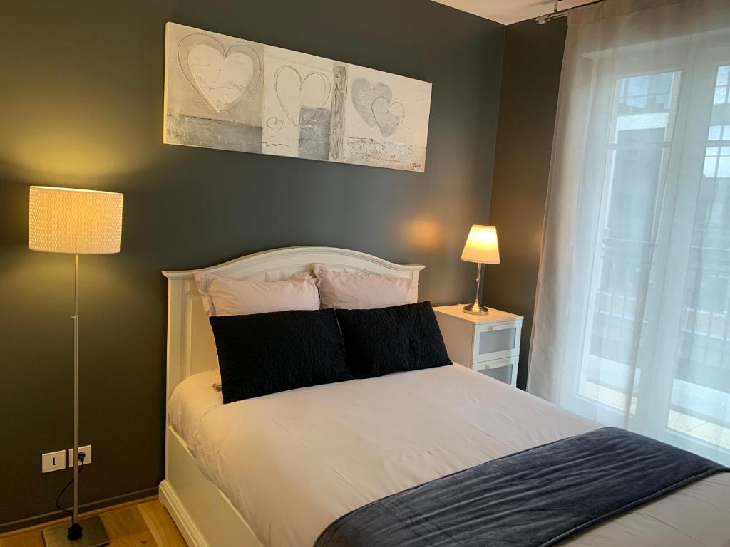 um quarto com uma cama com almofadas pretas e brancas em Appartement Disneyland au centre du Val d'Europe em Chessy