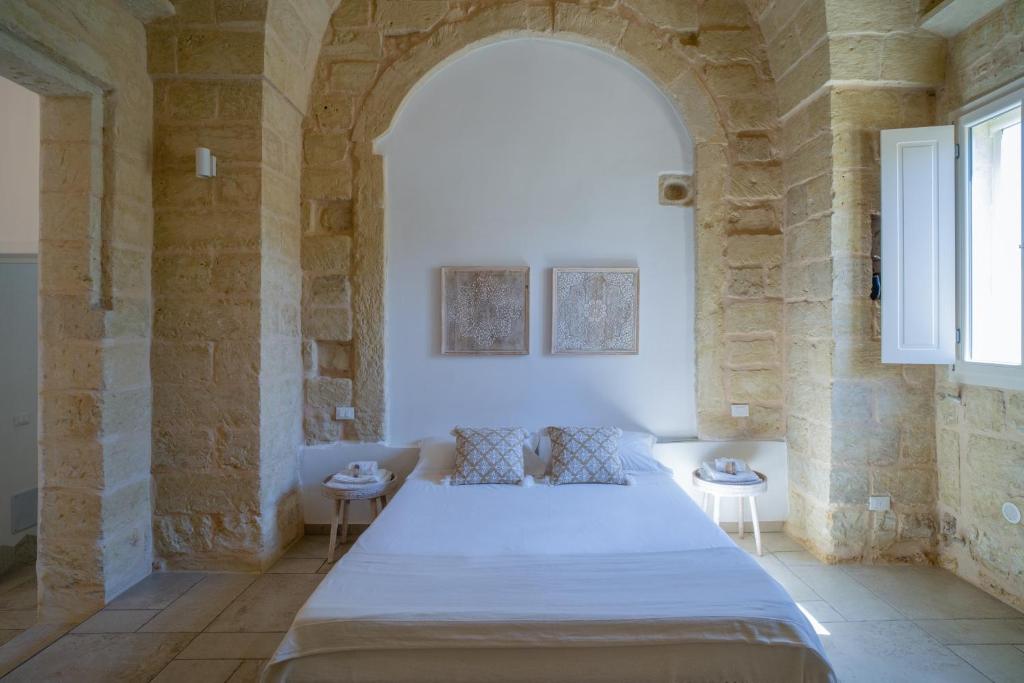 a bedroom with a large bed in a stone wall at Li Perrini Boutique B&B in Acquarica