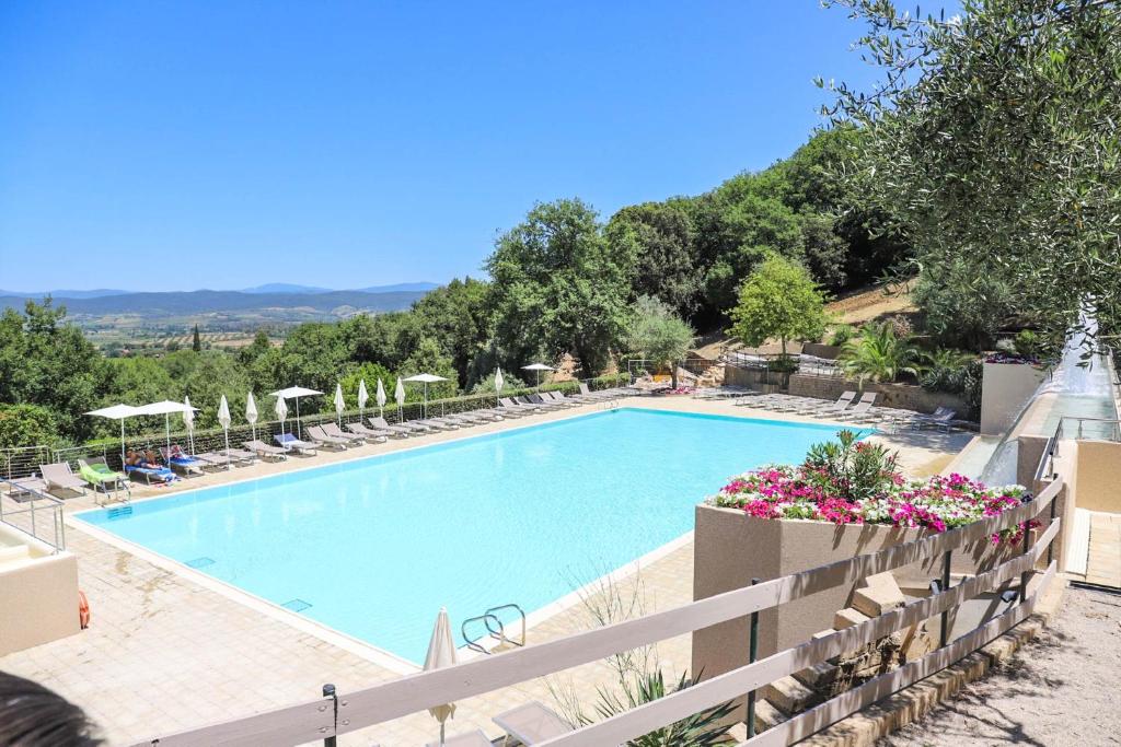 une grande piscine avec des chaises et des parasols dans l'établissement Vallicella Glamping Resort, à Scarlino