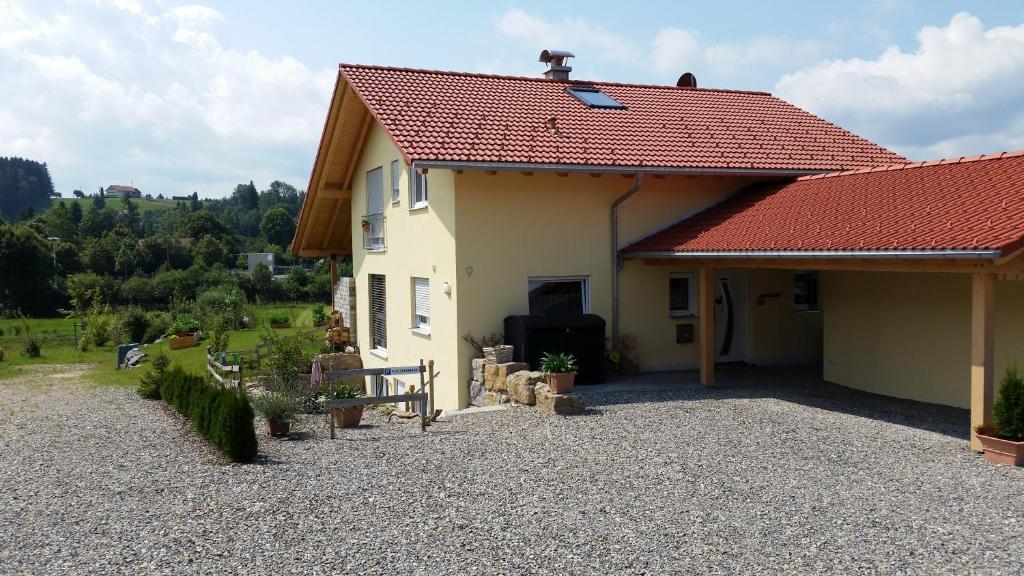 ein Haus mit rotem Dach und einem Kieshof in der Unterkunft Wilhelm-Tell-Str. in Altusried