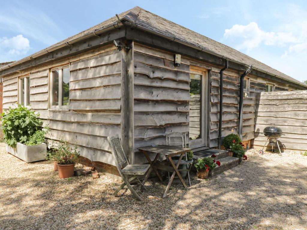 a wooden cabin with a table and a chair outside at Pond View in Fordingbridge