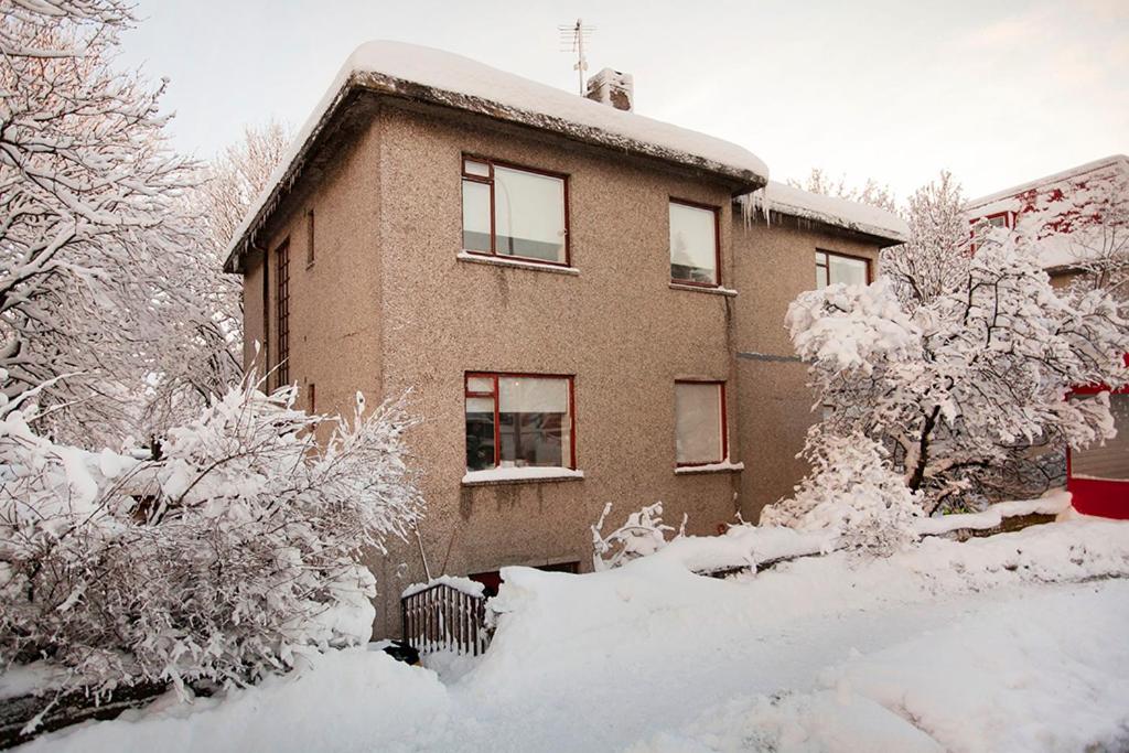 una casa cubierta de nieve con árboles y arbustos en Nordurey Guesthouse, en Reikiavik