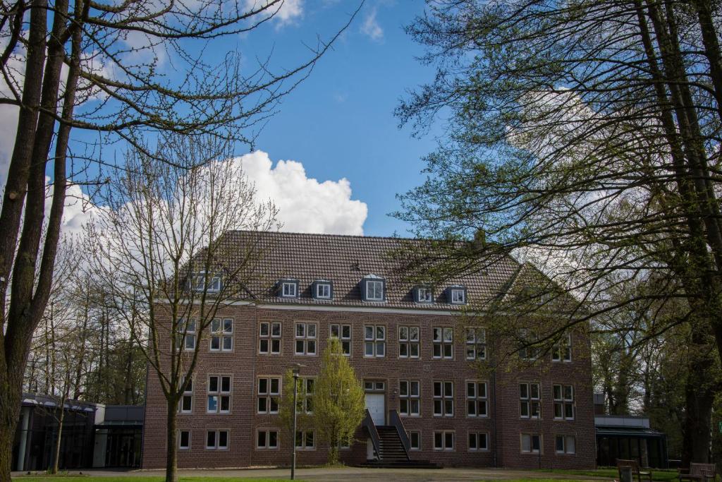 a large brick building with a black roof at Wasserburg Rindern in Kleve