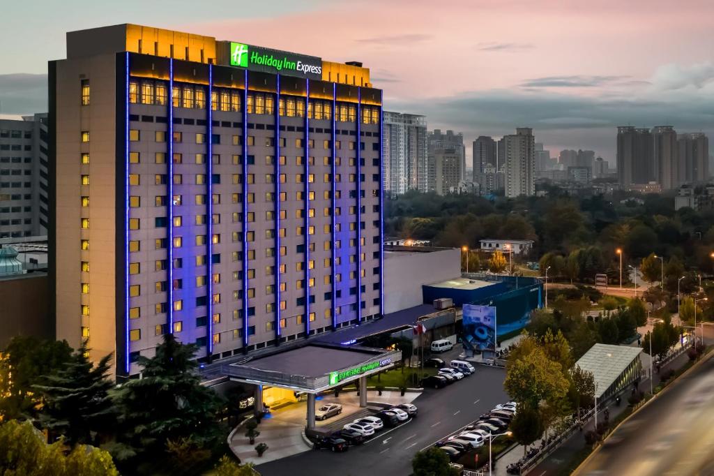 a hotel building with a parking lot in front of a city at Holiday Inn Express Zhengzhou Zhongzhou, an IHG Hotel in Zhengzhou