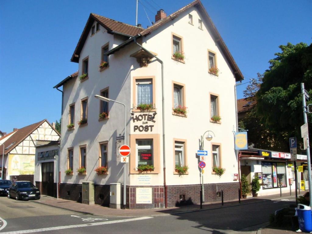ein weißes Gebäude an der Ecke einer Straße in der Unterkunft Hotel zur Post Schwanheim in Frankfurt am Main