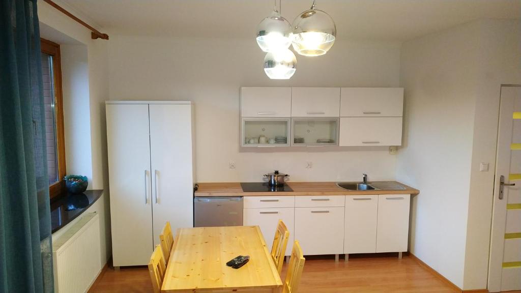 a kitchen with white cabinets and a wooden table at Apartament na Cisowej in Słupsk