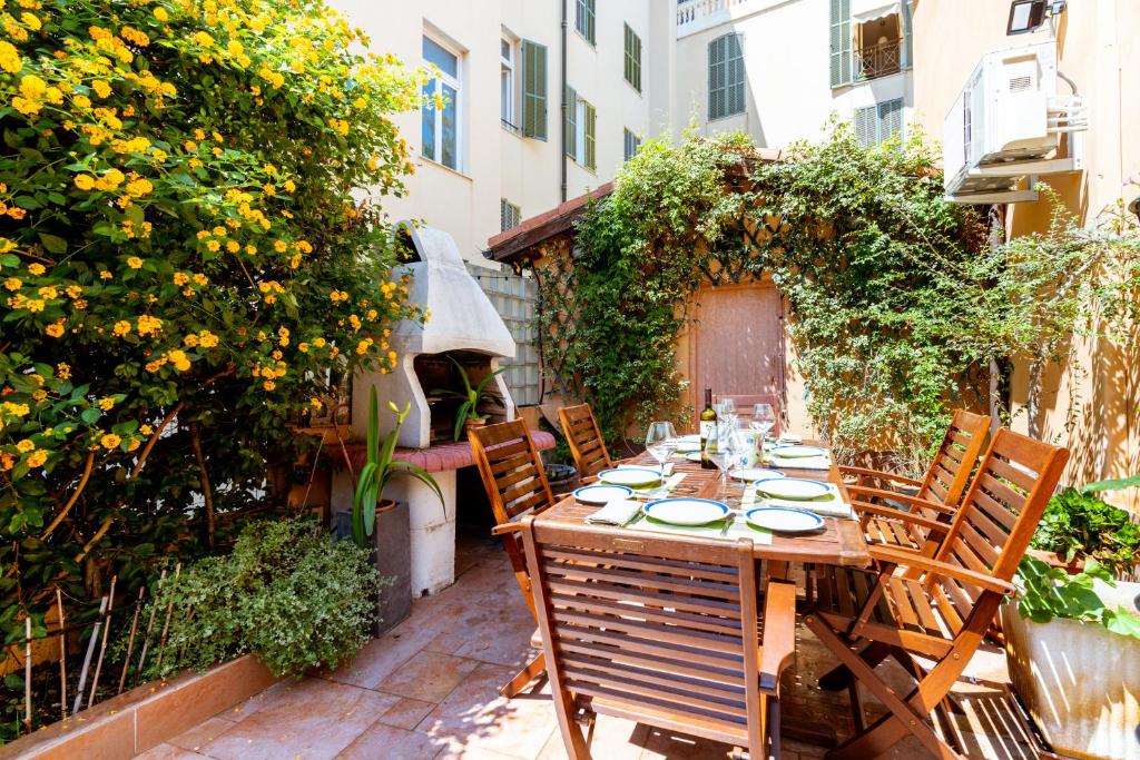 een houten tafel en stoelen op een binnenplaats met bloemen bij Villa Vallone Apartment in Bordighera