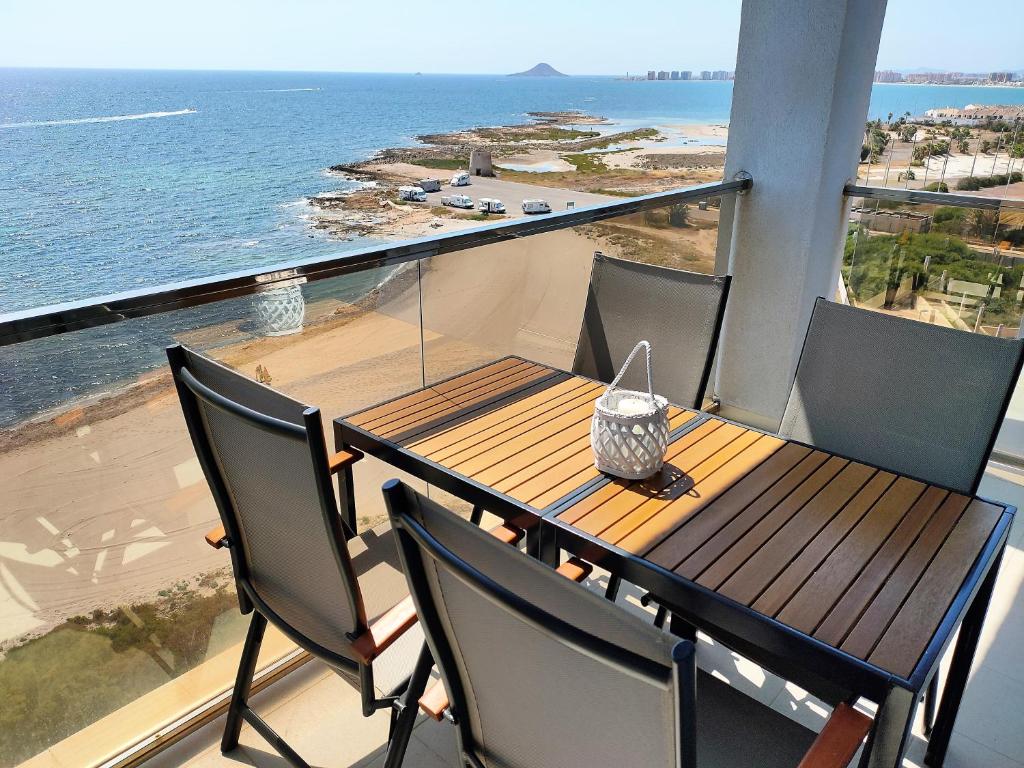 einen Tisch und Stühle auf einem Balkon mit Meerblick in der Unterkunft Veneziola Paraíso Apartament in La Manga del Mar Menor