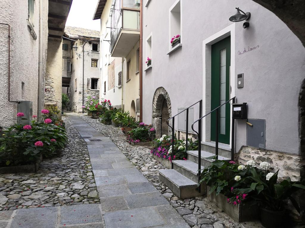 un vicolo fiorito e un edificio con porta verde di Appartamento CADELAVE a Villa di Chiavenna