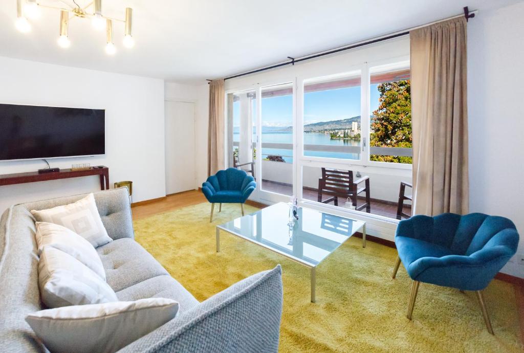 uma sala de estar com um sofá e cadeiras e uma grande janela em Sunset View Apartment - 2 Bedrooms em Veytaux