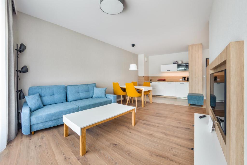 a living room with a blue couch and a table at Apartamenty Sun & Snow Bel Mare in Międzyzdroje
