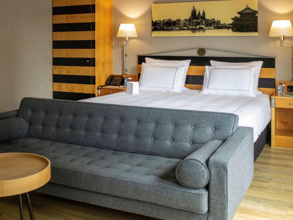 ein Schlafzimmer mit einem großen Bett und einem Sofa in der Unterkunft Swissôtel Amsterdam in Amsterdam