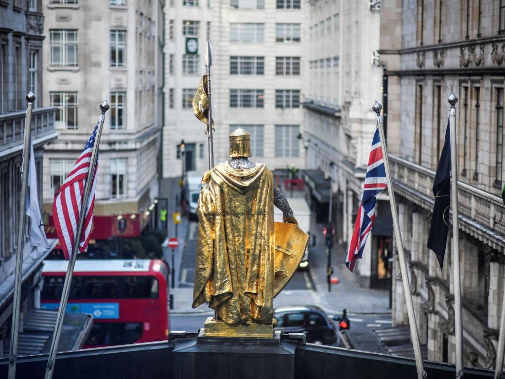 a gold statue in the middle of a street with flags at The Savoy in London