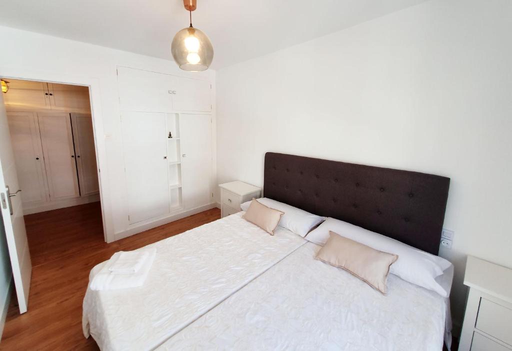 1 dormitorio con 1 cama blanca grande y cabecero negro en Ribera Beach Lux - Piso de lujo en Luanco, en Luanco