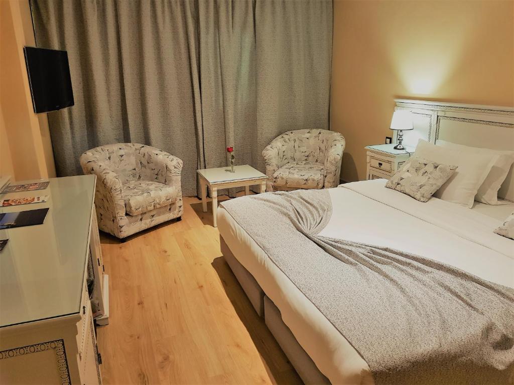 een hotelkamer met een bed en twee stoelen bij El Oumnia Puerto & Spa in Tanger