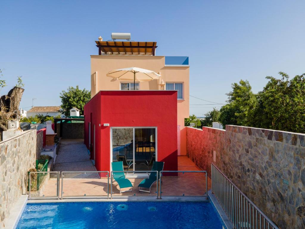 ein Haus mit einem Pool und einer roten Wand in der Unterkunft Casa Vela in Tavira