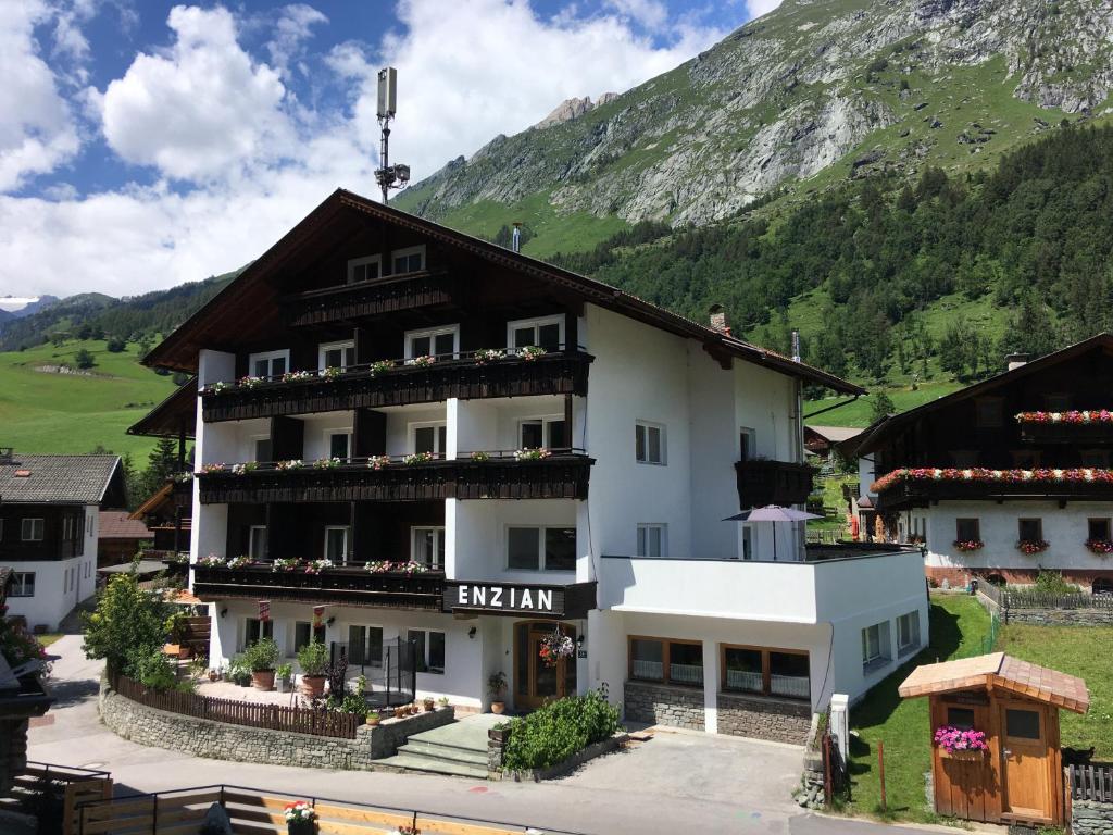 un grand bâtiment blanc avec une montagne en arrière-plan dans l'établissement Ferienhaus Enzian, à Prägraten am Großvenediger