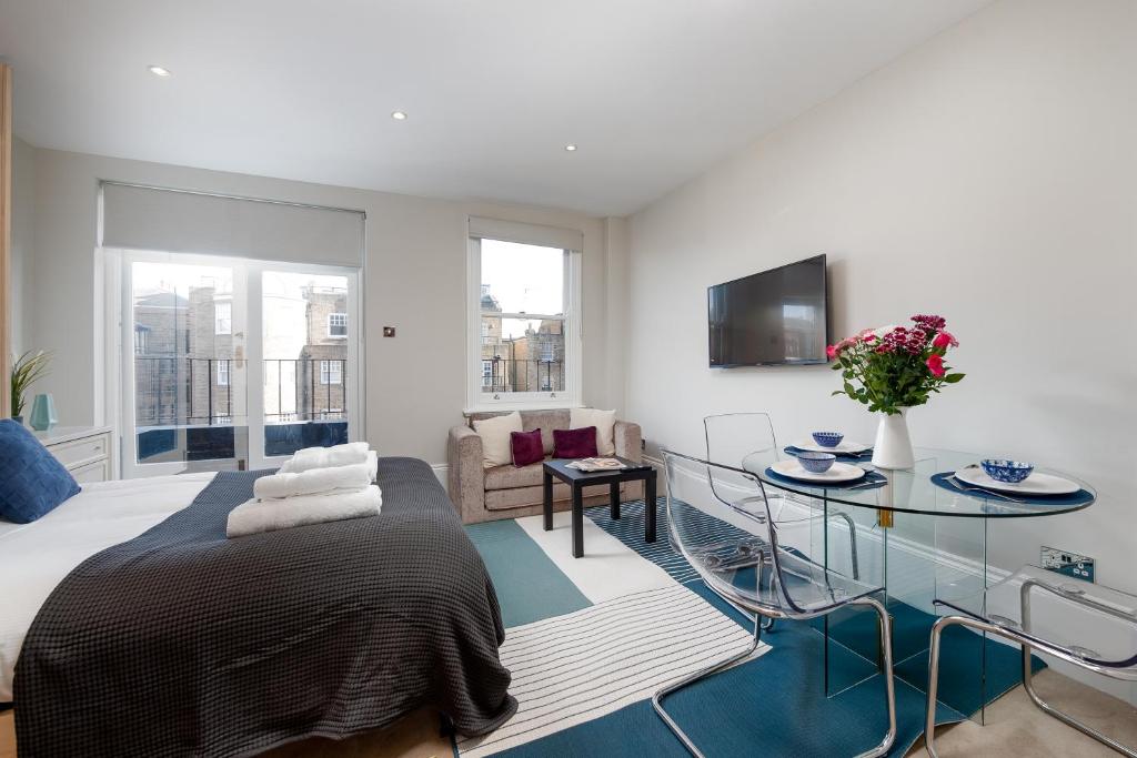 a bedroom with a bed and a glass table at CAPITAL Sloane Street Studio with Balcony in London