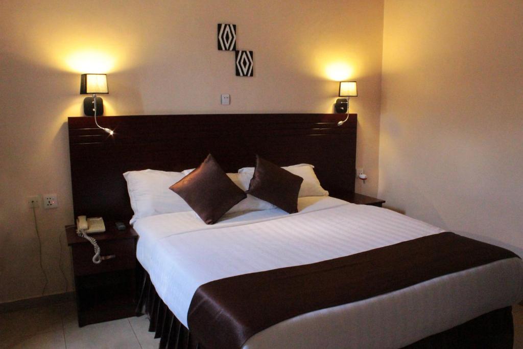a large bed in a hotel room with two lamps at Dereva Hotel Rwamagana in Rwamagana