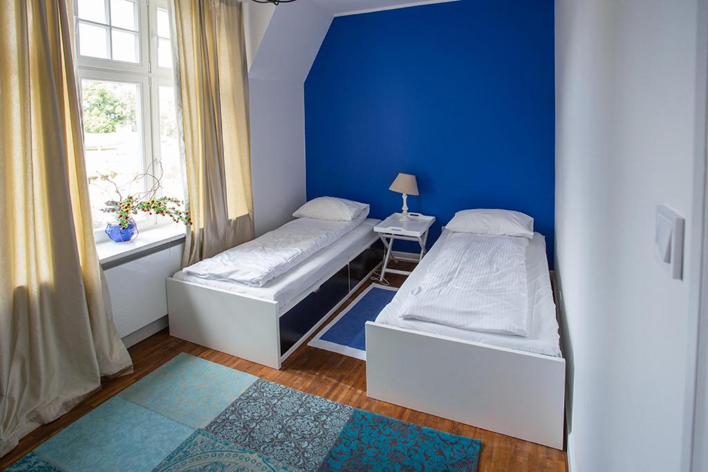 two beds in a room with a blue wall at Apartament Winieckiego in Sopot