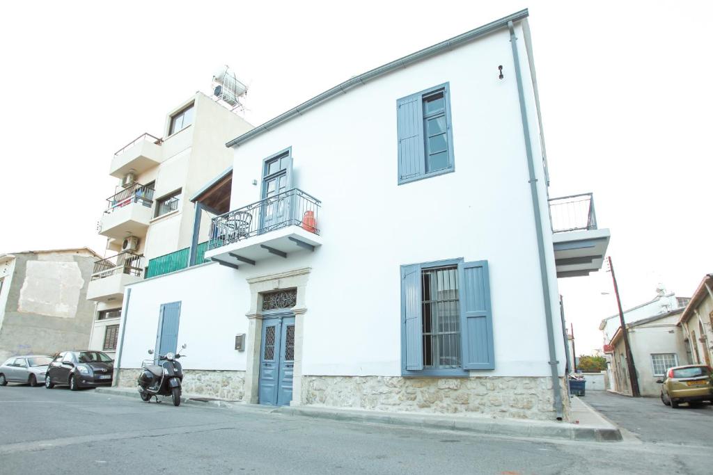 een wit gebouw met een scooter ervoor geparkeerd bij St. Lazaros Studios in Larnaka