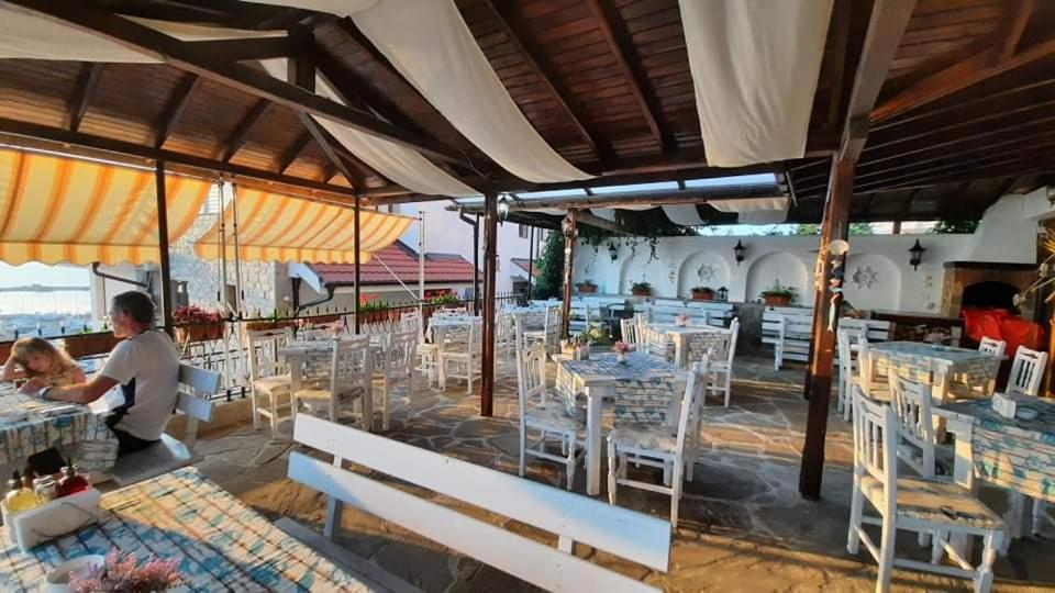 a restaurant with white tables and white chairs at ORION Guest House in Sozopol