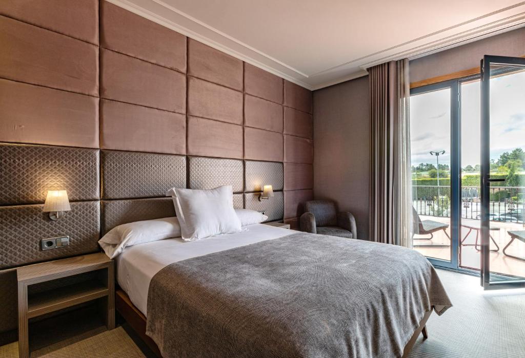 een hotelkamer met een bed en een balkon bij Hotel Pensua Punta del Este in Carballo