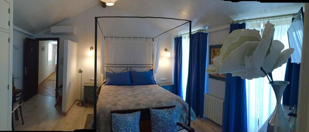 a bedroom with a canopy bed with blue pillows at Al Lago in Zahara de la Sierra