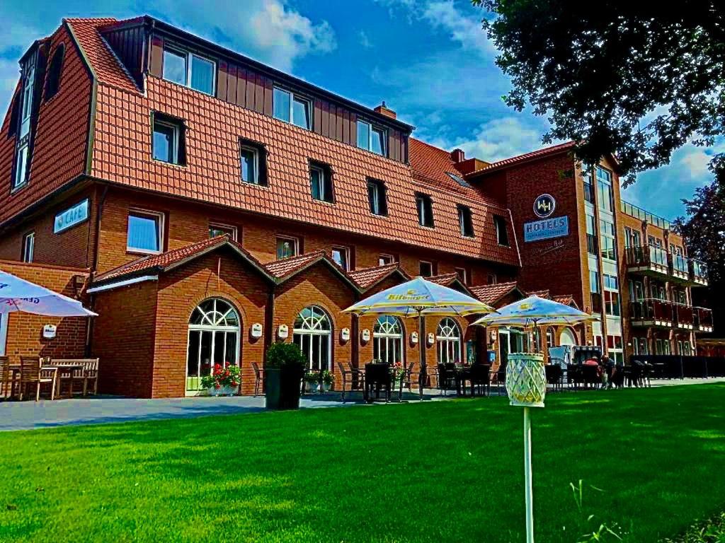 un grand bâtiment en briques avec des parapluies devant lui dans l'établissement WH Hotels Papenburg Zentrum, à Papenbourg