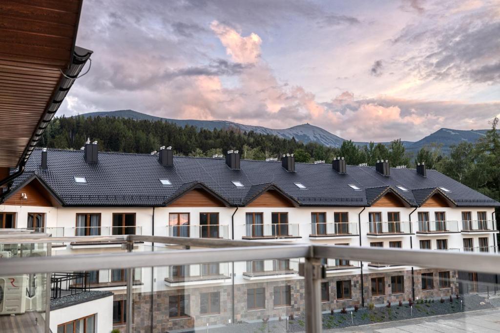 a building with a roof with mountains in the background at Sudecki Resort & SPA in Karpacz