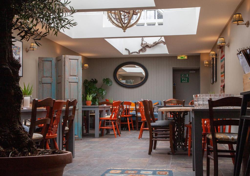 un restaurante con sillas, mesas y espejo en The Kings Arms Hotel, en Malmesbury