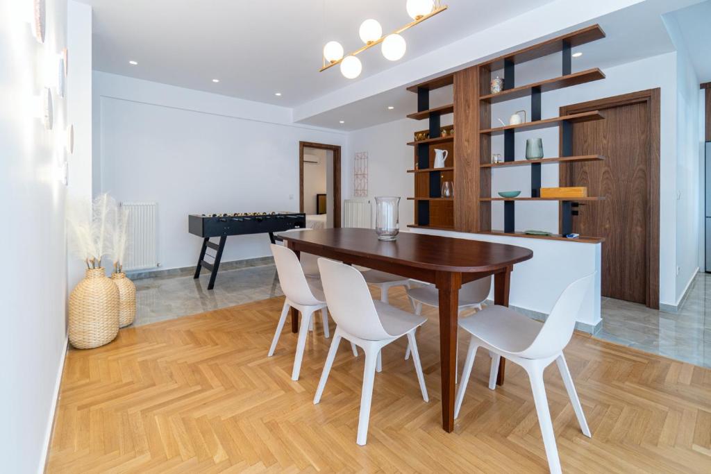 een eetkamer met een houten tafel en witte stoelen bij iKu Urban Apartment in Kavala