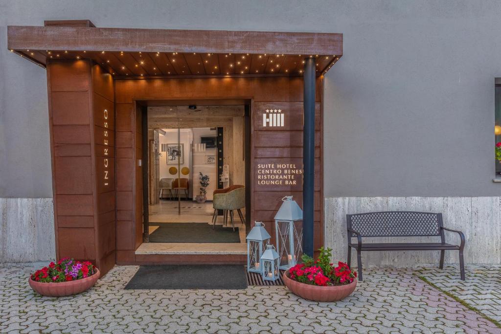 uma entrada para um edifício com dois vasos de flores e um banco em Hotel Miletto em San Massimo
