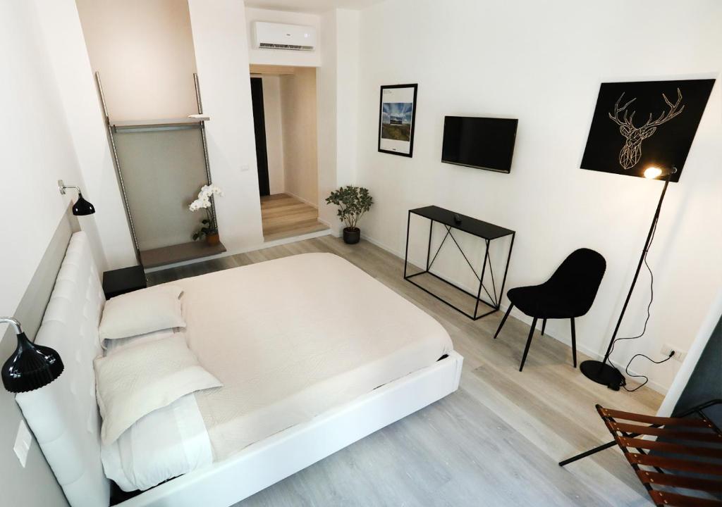 Cama blanca en habitación con escritorio y silla en b&b boutique four rooms bari, en Bari