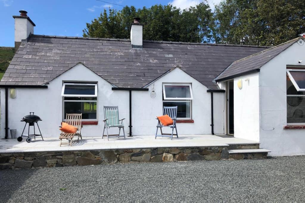 a white house with chairs sitting outside of it at Rooneys @ Ballymagreehan Explore and Unwind in Castlewellan