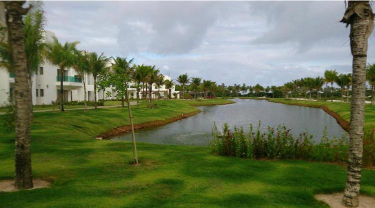 un parcours de golf avec un étang et des palmiers dans l'établissement Praia do Forte - Apartamento no Iberostar belíssimo, à Mata de São João