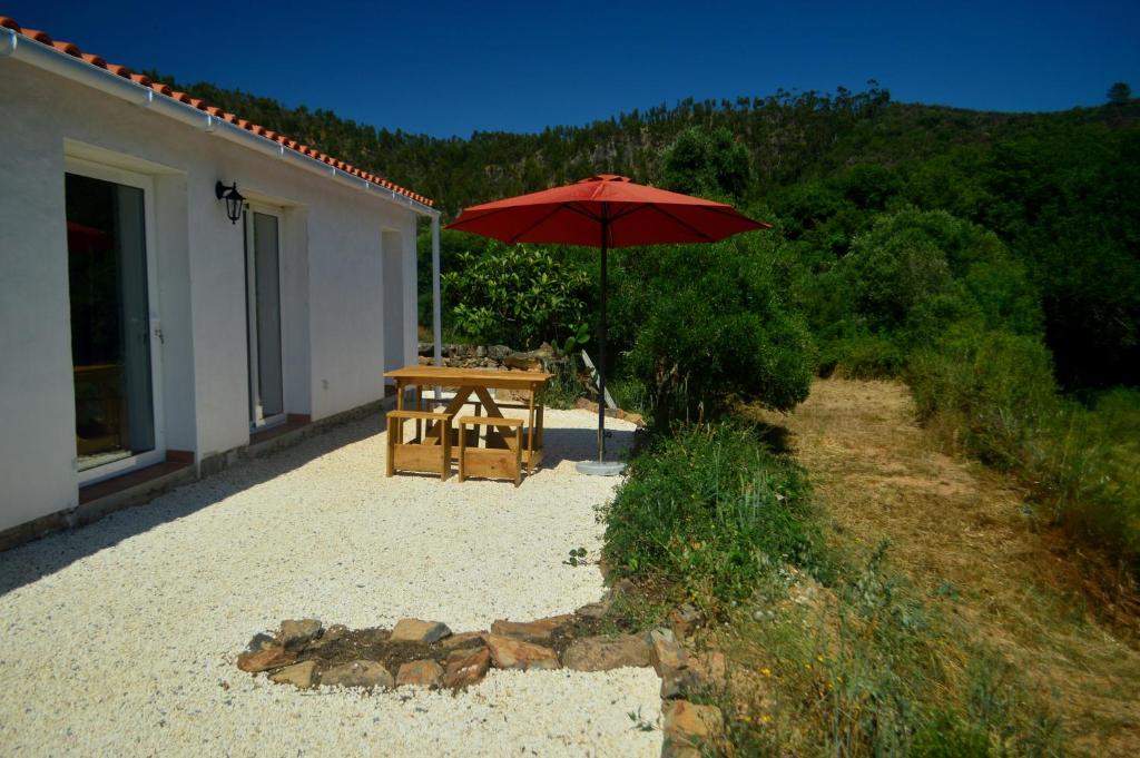 a table with an umbrella next to a building at Cozy house in beautiful valley, close to the beach in Odeceixe