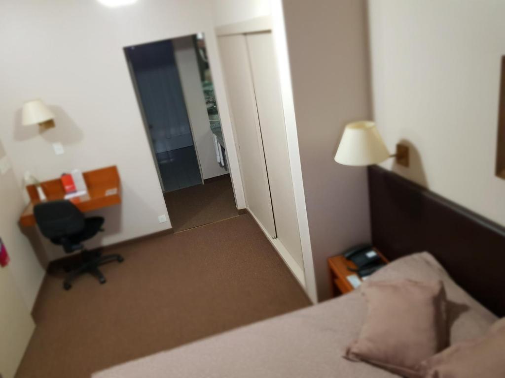 a bedroom with a bed and a desk and a chair at Comodoro Hotel in Comodoro Rivadavia