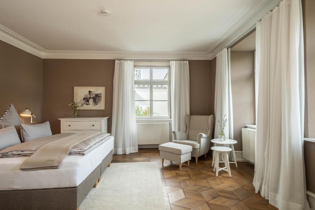 een slaapkamer met een bed, een stoel en een raam bij Schloss Kirchberg - Rosé in Immenstaad am Bodensee