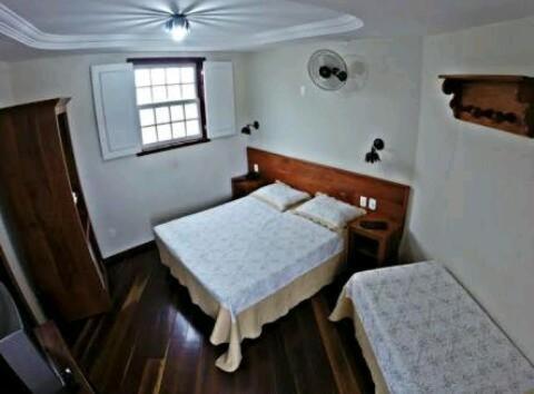 Habitación pequeña con 2 camas y ventana en Pousada dos Bandeirantes, en Ouro Preto