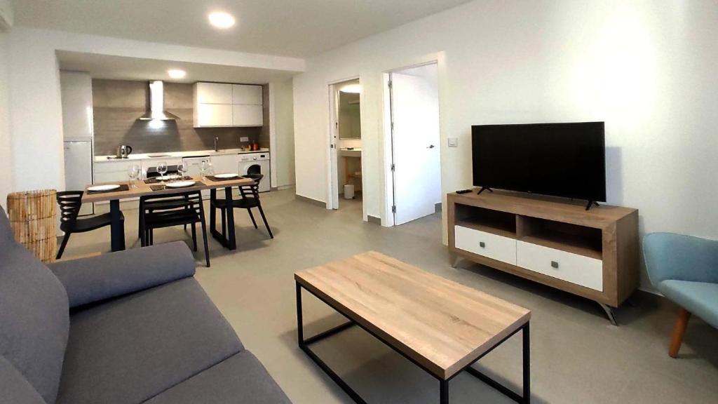 ein Wohnzimmer mit einem Sofa, einem TV und einem Tisch in der Unterkunft Apartamentos Lusitania Parking Gratis bajo disponibilidad in Merida
