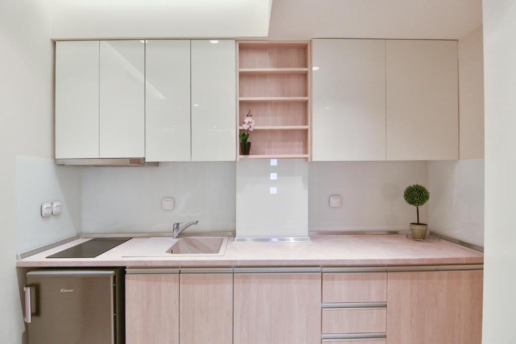a kitchen with white cabinets and a sink at On Board Luxury Studios in Sarti