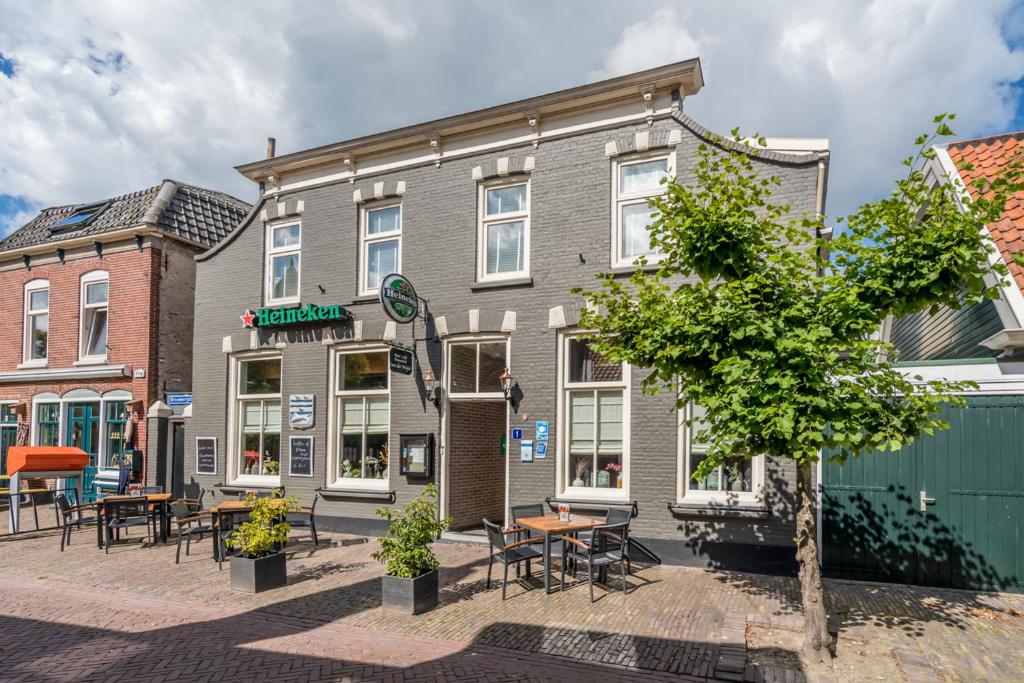 un bâtiment avec des tables et des chaises devant lui dans l'établissement Hotel-Restaurant van der Weijde, à Noordgouwe